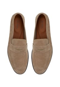Paire de mocassins beige en daim à enfiler avec un design cousu et des semelles intérieures en cuir, vus de dessus sur fond blanc.
