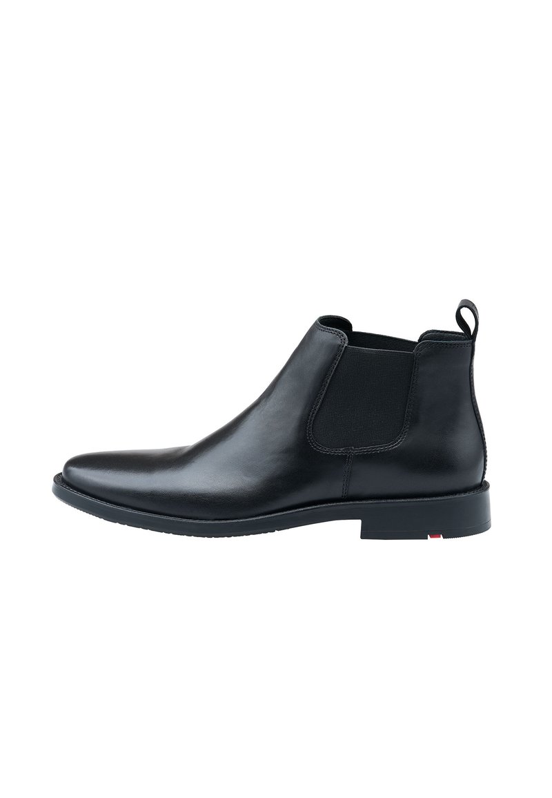 Stivale Chelsea in pelle nera con pannelli elastici laterali, superficie liscia, punta arrotondata e tacco basso. Presenta un passante sul retro.