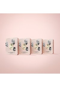 Set van vier vierkante cosmetische blikjes in crème en roze, met etiketten met productdetails, die verschillende formules tonen: hydraterend, balancerend, kalmerend en vochtinbrengend.