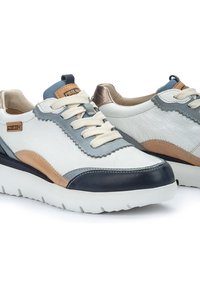 Zapatillas de piel blancas con acentos en azul, beige y marino, detalle texturizado en la parte superior y una suela blanca acolchada. Presenta cordones planos.