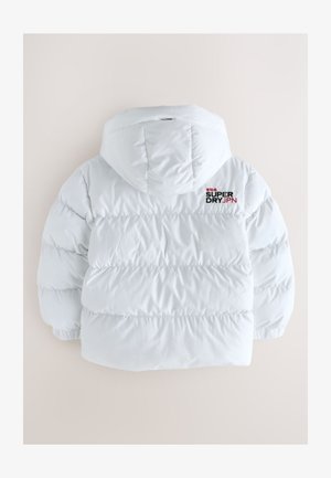 Doudoune blanche à capuche, avec des sections matelassées. Texte noir et rouge « SUPER DRY JPN » sur le haut du dos. Texture lisse et brillante.