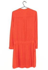 Long-sleeve dress in bright orange fabric, featuring a gathered waist and two side pockets. Smooth texture with buttoned cuffs.