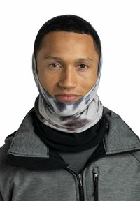Cuello multifuncional con un patrón de tie-dye en tonos de gris y negro. Tejido suave, ajuste ceñido, llevado debajo de una chaqueta gris con cremallera.