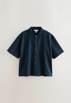 Granatowa koszula krótki rękaw z kołnierzykiem, z tkanym materiałem, z zapięciem na guziki z przodu oraz zaokrąglonym dołem.