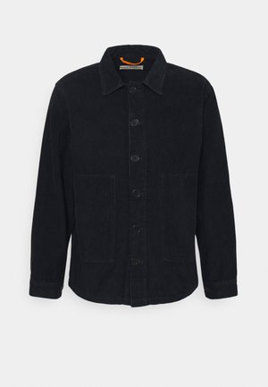 Zwarte corduroy jas met knopen, lange mouwen, kraag, twee opgestikte zakken aan de voorkant en een oranje lusdetail aan de binnenkant van de halslijn.