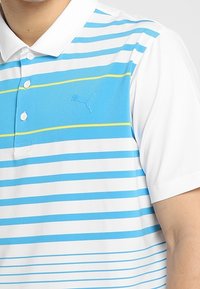 Polo à manches courtes pour homme avec col blanc, manches blanches, et rayures horizontales bleu, blanc et jaune, arborant un logo Puma.