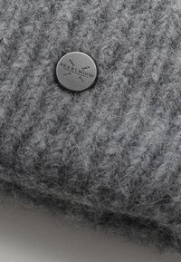 Cappello-beanie grigio lavorato a maglia con un morbido tessuto testurizzato e un bottone metallico circolare inciso con la scritta "PEARLWOOD."