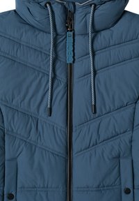 Giacca imbottita blu con motivo a zigzag, dotata di zip frontale, cappuccio regolabile e cordini. Tessuto testurizzato con dettagli neri.