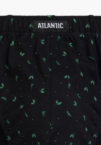 Czarne szorty z tkaniny z zielonym wzorem liści i małymi białymi kropkami. Elastyczny pas z naszywką "ATLANTIC" z przodu.