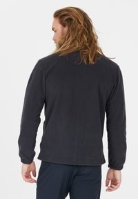 Sort fleecejakke med lange ærmer, ribbede manchetter og en afslappet pasform. Blød tekstur, ingen synlige mønstre, designet til afslappet brug.