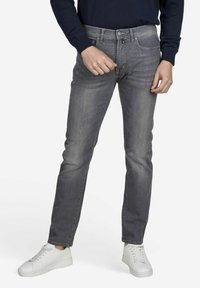 Grijze denim jeans met een slim fit, met een medium taillehoogte, standaard vijf-pocket ontwerp en contrasterende stiksels, gecombineerd met witte sneakers.