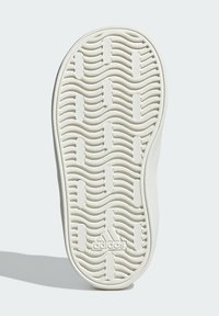 Suola di scarpa in gomma bianca con motivi a onda testurizzati e logo Adidas. Bordo arrotondato e superficie liscia con multiple scanalature per trazione.