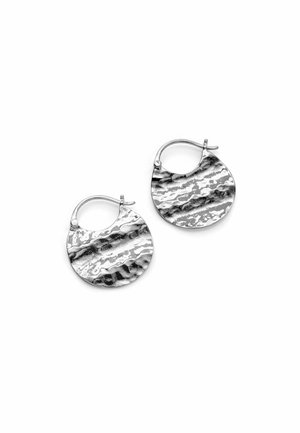 Par de pendientes de aro redondos de metal martillado con una superficie texturizada y ondulada, y cierre de palanca, sobre un fondo blanco.