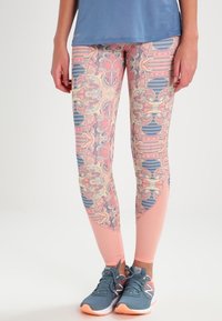 Leggings avec un motif en rose, bleu et pêche. Le matériau présente une texture douce avec des accents en maille au bas des jambes.