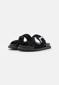 Black suede sandals with two wide straps, silver buckle on top strap, and thick textured rubber sole designed for casual wear.