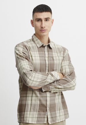 Camisa de cuadros marrón y crema de botón en tejido ligero, que presenta un bolsillo en el pecho y un cuello clásico. Textura suave con patrones contrastantes.