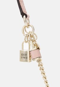 Ciondolo in metallo con una serratura incisa "EST 1981", attaccato a un cinturino in pelle texturizzata rosa e catene dorate. Finiture sia lucide che opache.