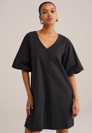 Abito nero a maniche corte con scollatura a V, caratterizzato da una vestibilità comoda, tessuto testurizzato e aperture laterali, che mostra una finitura liscia.