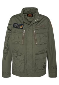 Olivengrøn militærstil jakke, lavet af bomuldsblanding, med flere forlommer, lynlåsåbninger og trykte patches med tekst og grafik.