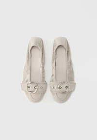 Bailarinas de ante gris con punta redondeada, correa decorativa con una hebilla circular de metal y una parte superior de textura suave.