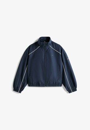Dunkelblaue Jacke mit Reißverschluss, weißer Paspelierung an Ärmeln und Schultern, elastischen Bündchen und Saum sowie kleinem Logo auf Brust und Ärmel.