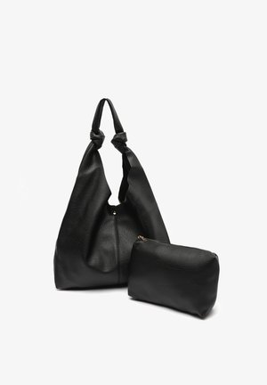 Sac fourre-tout en cuir noir texturé avec des anses nouées et une petite pochette zippée assortie à côté sur fond blanc.