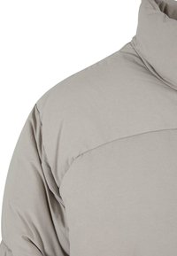 Chaqueta acolchada de color gris claro con un alto cuello, textura de acolchado visible y un acabado liso y mate. Presenta una costura a lo largo del hombro.