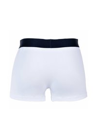 Boxers en coton blancs avec une ceinture élastique bleu marine, présentant un design simple et une texture lisse, coupés au-dessus des cuisses.