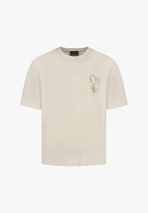 Camiseta de algodón color crema con mangas cortas, que presenta un gráfico de corazón verde y un logo en el lado izquierdo. Corte regular.