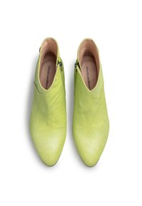 Zapatos de punta en un brillante verde lima, con una textura suave, parte superior de tela blanda y cremalleras en ambos lados para facilitar su uso.