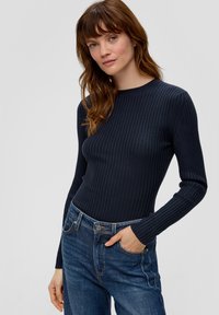 Navy gestreiftes Langarmshirt mit Rundhalsausschnitt, kombiniert mit blauen Jeans im klassischen Schnitt und mit Fronttaschen.