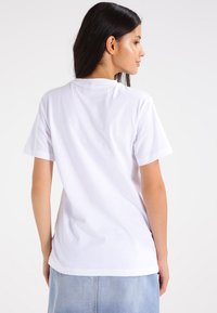 Hvit kortermet t-skjorte laget av bomull, med klassisk passform og en enkel bakdesign med rund hals.