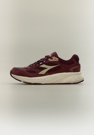 Bordeauxfarbener Sportschuh mit cremefarbiger Sohle und Logo, Mesh- und Wildlederobermaterial sowie Schnürung, seitlich auf neutralem Hintergrund gezeigt.