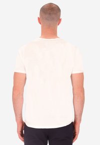 T-shirt a maniche corte, con collo a giro in cotone avorio con una texture liscia. Presenta un orlo dritto e dettagli di cucitura minimi.