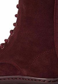 Bottine en nubuck bordeaux avec un panneau latéral texturé, des lacets en tissu et des œillets ronds. Caractéristiques de surpiqûres contrastées et d'une semelle en caoutchouc.