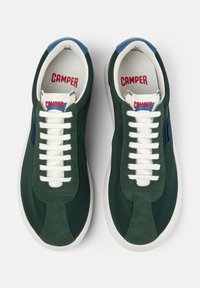 Vihreät mokkasneakersit valkoisilla nauhoilla, joissa on sininen yksityiskohta kantapässä ja "CAMPER" -brändäys kielekkeessä ja sisäpohjassa.