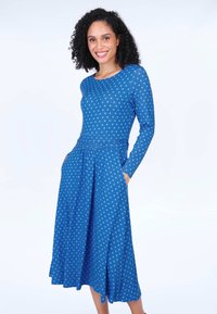 Blaues langärmeliges Kleid mit grünen Pünktchen, Taillendetail, fließendem Rock und Taschen. Glatter Stoff mit entspannter Passform.