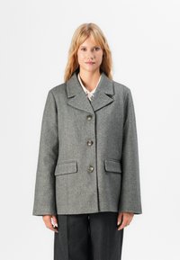 Giacca in misto lana a motivo chevron grigio, con colletto a revers, cinque bottoni e due tasche frontali, caratterizzata da una vestibilità comoda e una finitura texture.