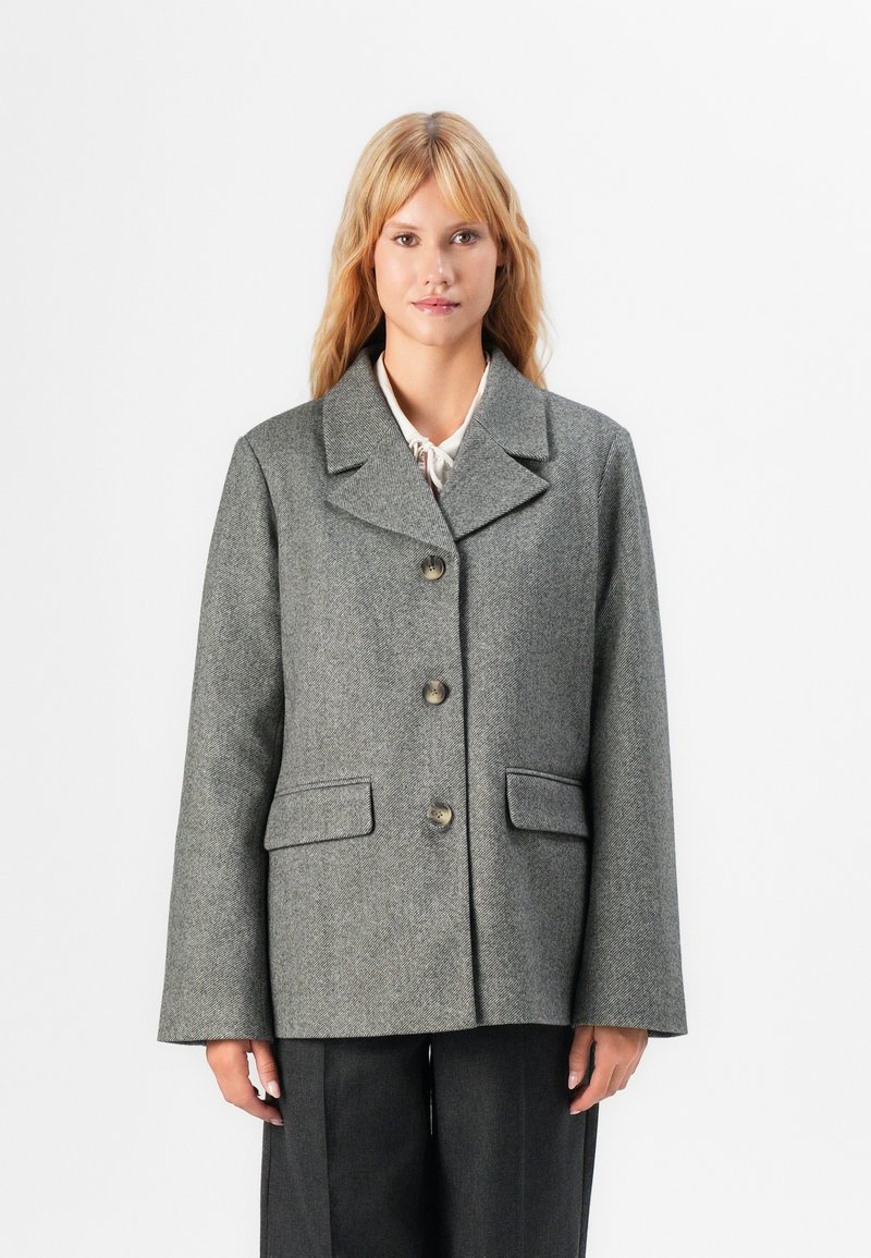 Giacca in misto lana a motivo chevron grigio, con colletto a revers, cinque bottoni e due tasche frontali, caratterizzata da una vestibilità comoda e una finitura texture.