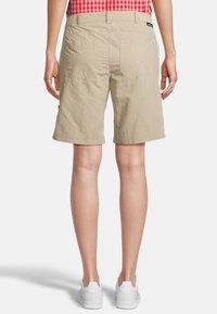 Beige Shorts mit einer lockeren Passform, ausgestattet mit zwei Gesäßtaschen und einer glatten Textur, kombiniert mit weißen Sportschuhen.