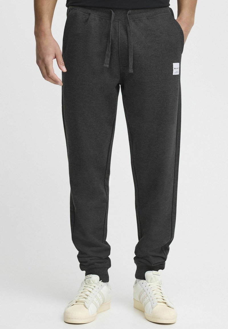 Kullgrå sweatpants med elastisk talje, snor, sidelommer og et lille mærke på venstre lår.