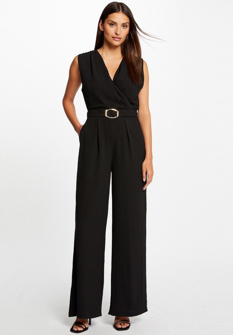 Zwarte jumpsuit met een wikkelontwerp, zonder mouwen, een getailleerde taille met een gouden gesp en brede, vloeiende pijpen. Gladde textuur en minimale accenten.