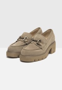 Mocassins en daim beige avec un talon plateforme épais, ornés d'une boucle décorative et de détails de couture ; texture lisse et boîte à orteils large.