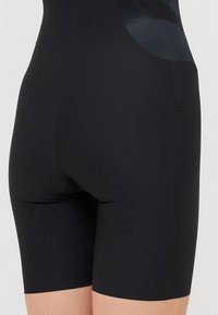 Black cycling shorts made from stretchy fabric, featuring a smooth texture and a fitted design that extends to mid-thigh length.