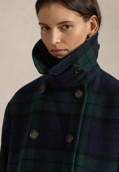 Kaksteist nööbitud tumeroheline ja tumesinine ruuduline villane mantel, millel kõrge krae ja ümarad nupud. Pehme tekstuur ja struktureeritud lõige.