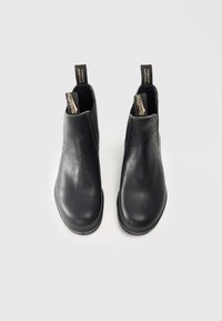 Bottines en cuir noir avec panneaux latéraux élastiques, une finition lisse et des languettes de tirage avec des étiquettes de marque. Bout rond et semelle plate.