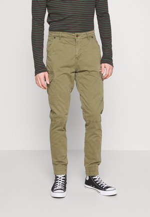 Pantalons cargo olive avec une coupe fuselée, de multiples poches latérales, des poignets élastiques et une fermeture à bouton. Assortis à des baskets montantes noires.