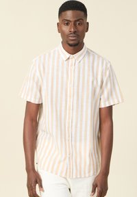 Camicia a maniche corte con bottoni, caratterizzata da strisce verticali bianche e giallo chiaro, realizzata in tessuto leggero, con una texture morbida.