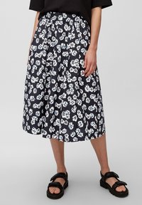 Falda midi floral en azul marino con patrón floral en blanco y azul, diseño plisé, cinturilla elástica, combinada con sandalias negras de suela gruesa.