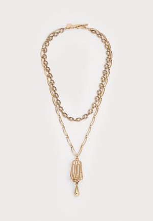 Collier en or superposé avec deux styles de chaînes différents et un pendentif avec un charme en forme de goutte au bas.
